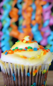 One cupcake with sprinkles and ribbons hanging in the background.  Used a shallow depth of field and selective focus on the middle part of cupcake and sprinkles.