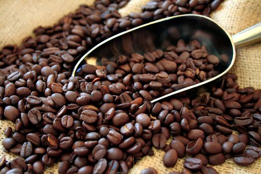 Coffee beans being scooped up on a background of burlap.
Used a shallow depth of field with selective focus.