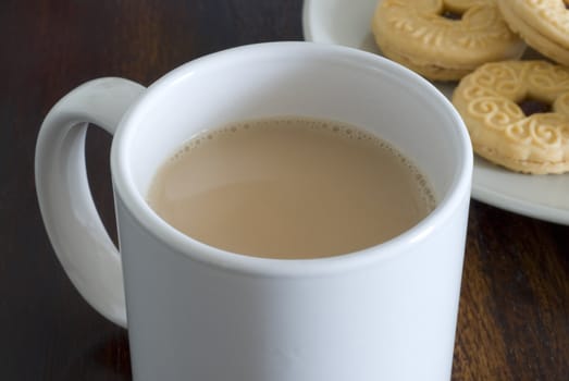a mug of white tea and plate jam biscuits