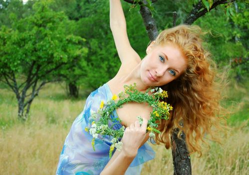 Redhead girl with flower diadem in garden with flying hair