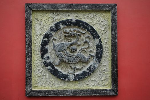 bronze dragon sculpture on a red wall