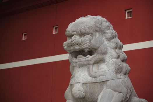 stone lion statue before the red wall