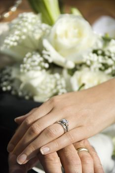 Caucasian mid-adult male and female hands with wedding rings.