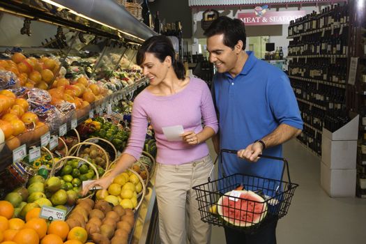 Caucasian mid-adult couple grocery shopping for fruit.