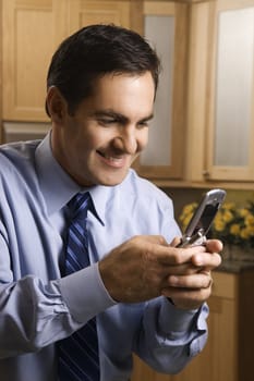 Mid-adult Caucasian male holding cell phone and smiling in kitchen.