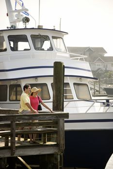 Mid-adult Caucasian couple at dock with boat in background.