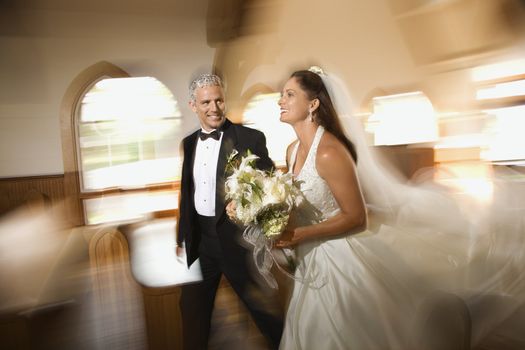 Bride and groom leaving church with motion blur effect.