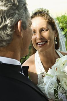 Looking over groom's shoulder at smiling bride.