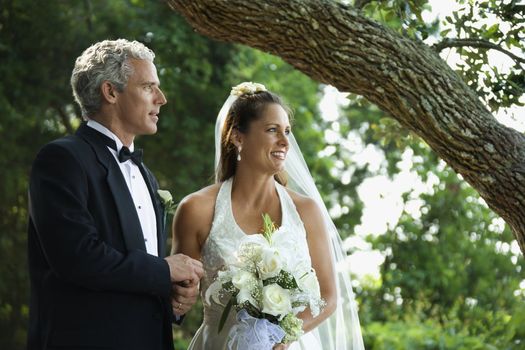 Portrait of bride and groom holding hands outside.