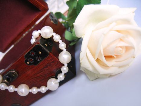 string of pearls in jewelery box and rose