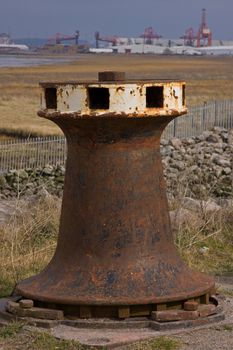 Capstan on disused harbourside with Avonmouth docks on the horizon