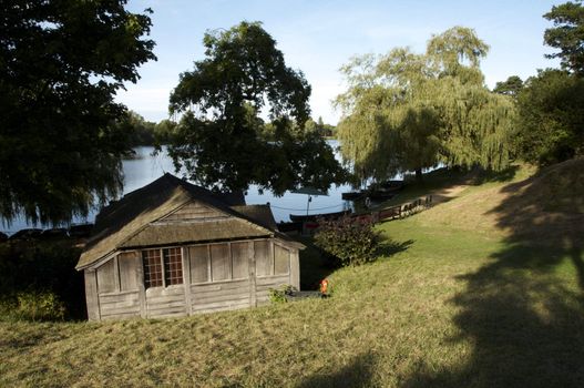 A wooden boathouse by a lake with trees in a background