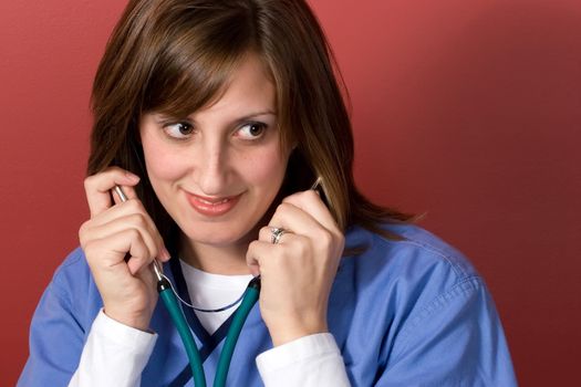 This nurse is listening with her stethoscope isolated over a red background.