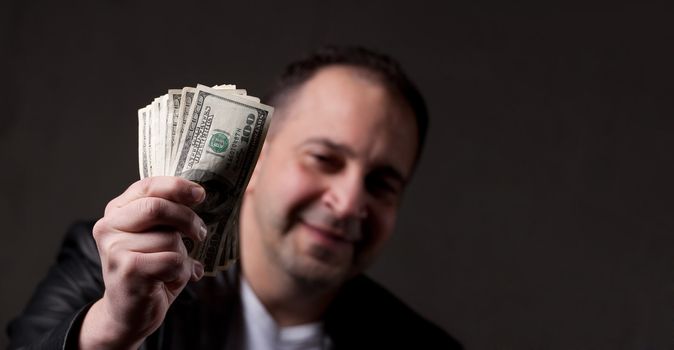 A happy middle aged man holding a handful of money with copyspace.