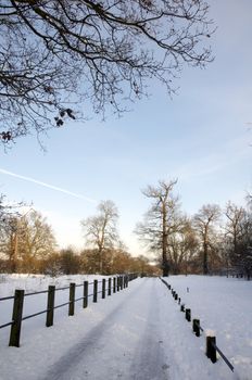 A footpath covered in snow with a fence