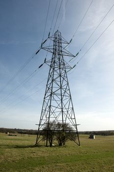 An electrical pylon in a field with a blue sky