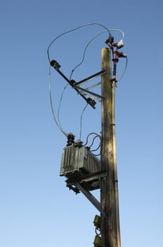 A wooden pole with power line and transformer on top