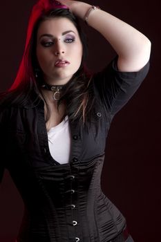 Goth girl with pink hair and body piercing holding her black and pink hair