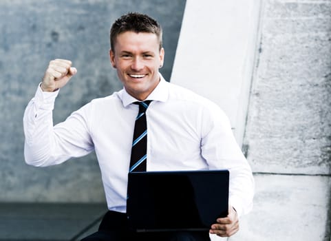 Young Elated Corporate Man With Laptop Showing His Success