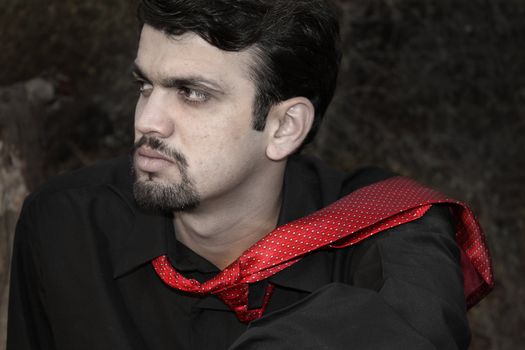A portrait of a frustrated Indian executive wearing a stylish red tie and black shirt.