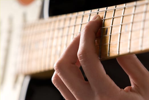 Hand playing guitar chord with shallow depth of field. 