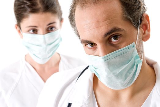 Adult doctor and young nurse with mask on white background, focused on doctor. 