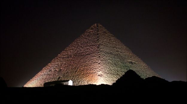 Giza Pyramids and sphinx illuminated by colored lights at night