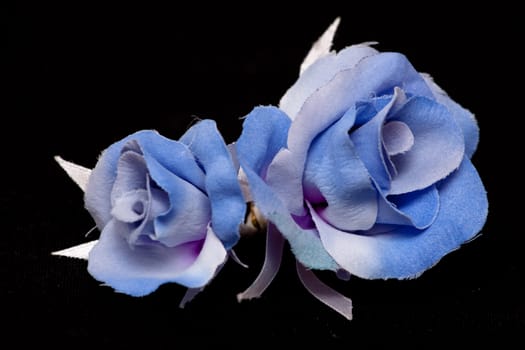 two artificial blue handmade roses on black
