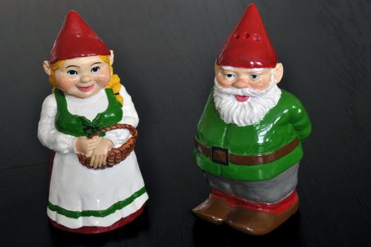 Cute set of salt and pepper shakers designed as dwarfs on dark wooden table