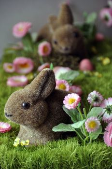 Easter decoration with rabbits, eggs and daisies on faked grass
