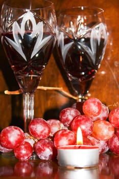 glasses of wine, candle light, a bunch of grapes, crystal glasses, dark wine, two fougeres