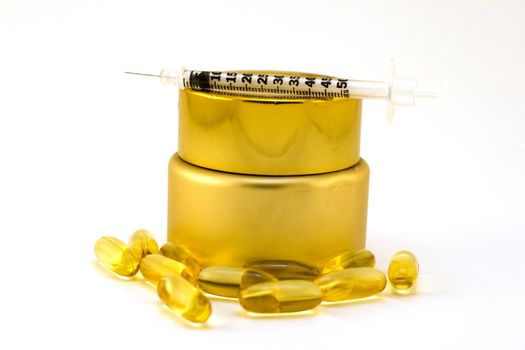 Cosmetic product in gold container with pills and needle