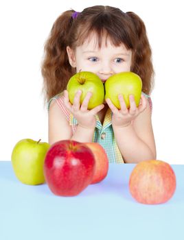 Girl playing with ripe apples sitting at the table