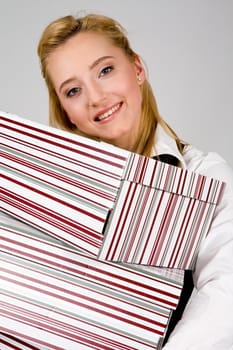 Smiling young woman holding a stack of boxes indoors