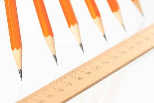 Few wooden yellow pencils in a row and ruler on white background