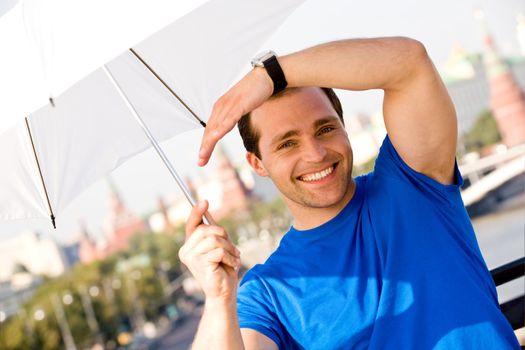 Smiling caucasian man holding white umbrella in Moscow City