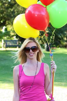 Beautiful young blond lady with a bunch of brightly colored balloons