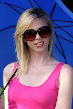 Gorgeous blonde woman wearing sunglasses and  holding a blue sun umbrella