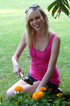 Beautiful blonde woman working in a flower bed outdoors