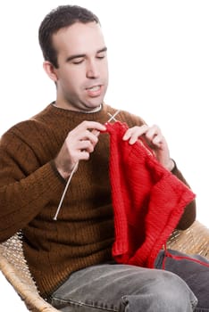 A young man knitting a red cloth, isolated against a white background