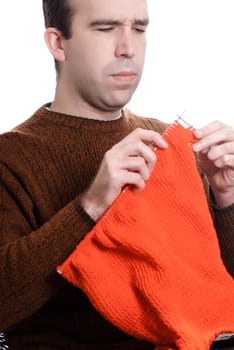 A young man is knitting something while sitting down, isolated against a white background