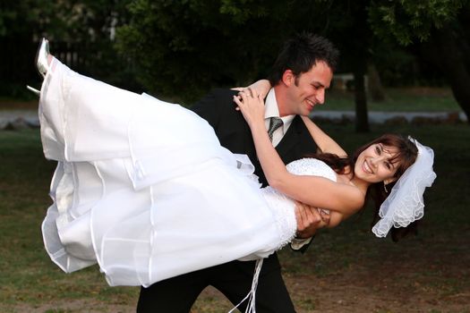 Beautiful wedding couple with groom lifting his smiling bride