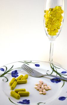 vitamins and pills on white plate with wine glass