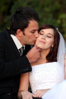 Groom kissing his lovely bride on her cheek on their wedding day
