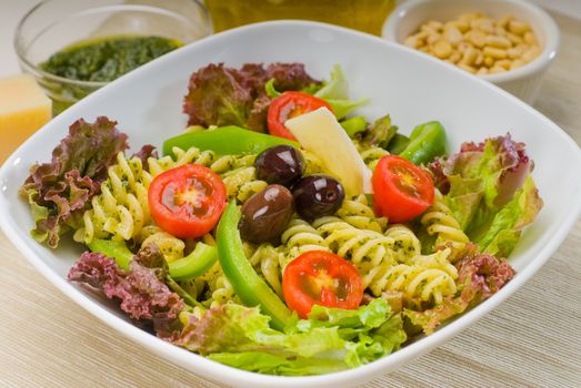 fresh healthy homemade italian fusilli pasta salad with parmesan cheese,pachino cherry tomatoes, black olives and mix vegetables ,dressed with extra-virgin olive oil and pesto sauce