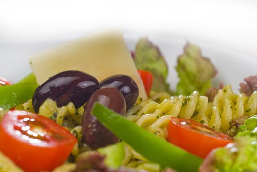 fresh healthy homemade italian fusilli pasta salad with parmesan cheese,pachino cherry tomatoes, black olives and mix vegetables ,dressed with extra-virgin olive oil and pesto sauce