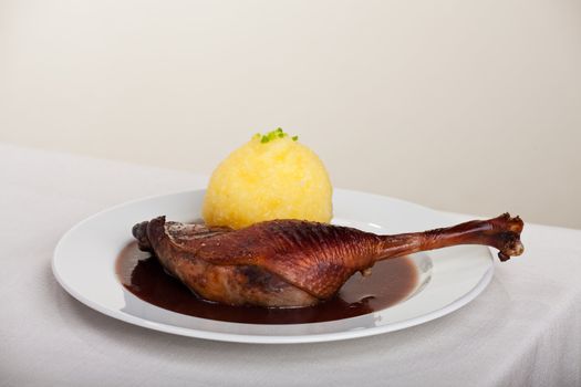 roasted goose leg on linen tablecloth