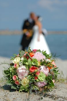 bouquet, bride and groom. The focus is on the bouquet and the bride and groom are in blur.