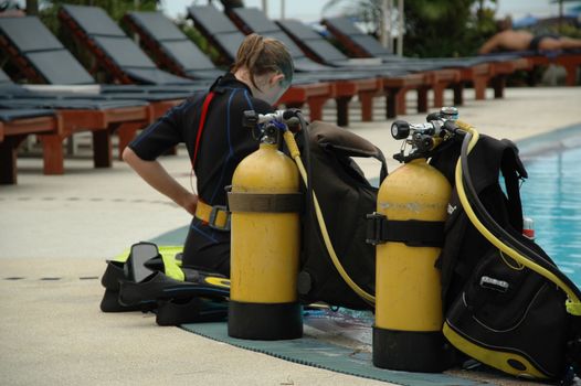 Diver at the swimmingpoll getting ready. The diver sits on the edge of the pool.