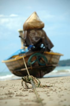 Boat and rope on a sandy beach. The focus is on the middel of the rope.